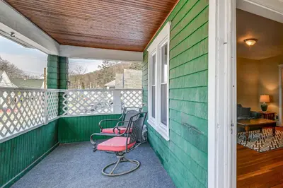 a green house with two chairs on a porch at 1 Mi to Dtwn Binghamton Apt with Covered Balcony! in Binghamton