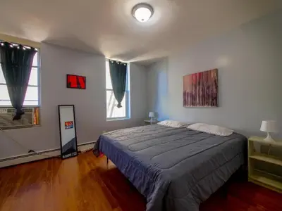 a bedroom with a large bed and two windows at Sleek one-bedroom abode near NYC in Jersey City