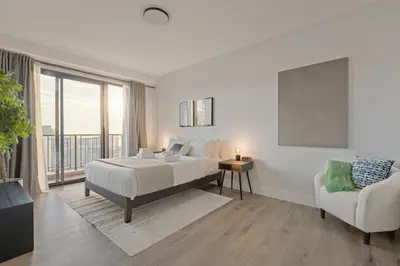 a white bedroom with a bed and a chair at Modern Retreat Free Parking 30Min NYC in Bayonne