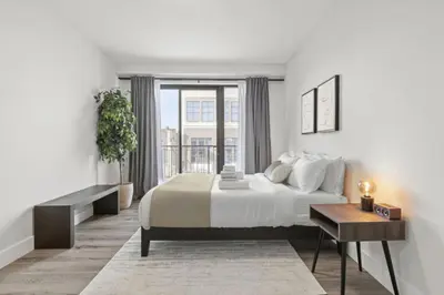 a white bedroom with a large bed and a table at Modern Retreat Free Parking 30Min NYC in Bayonne
