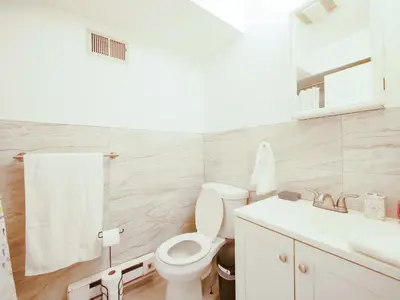a white bathroom with a toilet and a sink at Deluxe 2-Bedroom Apt minutes from NYC in Jersey City