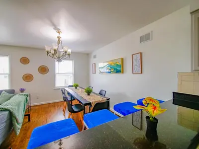 a living room with a dining room table and blue chairs at Impressive 3bed 2bath apt close to NYC in Jersey City