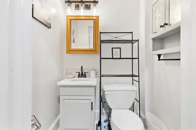 a white bathroom with a toilet and a mirror at Main Line Manor 3BR with King Beds & Patio & Backyard in Bryn Mawr
