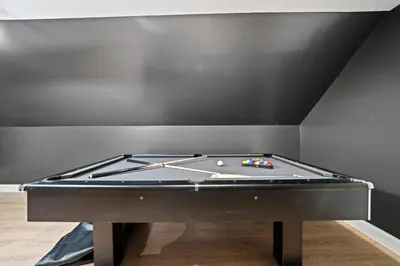 a pool table in a room with a black wall at Spacious Luxe Stay Sleeps 16 20 Min to NYC in Bayonne