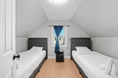 two beds in a room with a window at Spacious Luxe Stay Sleeps 16 20 Min to NYC in Bayonne