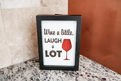 a framed picture of a wine a little laugh a lot at Lovely 3BR Homewith free parking-WALK to WP Gate in Highland Falls
