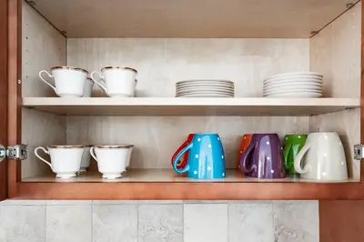 a shelf with cups and plates on it at Lovely 3BR Homewith free parking-WALK to WP Gate in Highland Falls