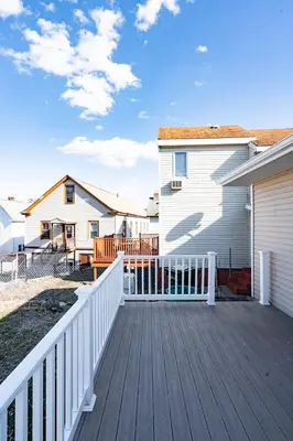 a wooden deck with a white fence next to a house at Lovely 3BR Homewith free parking-WALK to WP Gate in Highland Falls