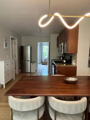 a kitchen with a wooden table and white chairs at NEW! Historic Townhouse-14 min to WTC in Jersey City