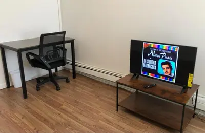 a television sitting on a table with a desk and a chair at Private one-bedroom and one-bathroom apartment with private street entrance in convenient area, MetLife Stadium FIFA World Cup 35 minutes away in Perth Amboy