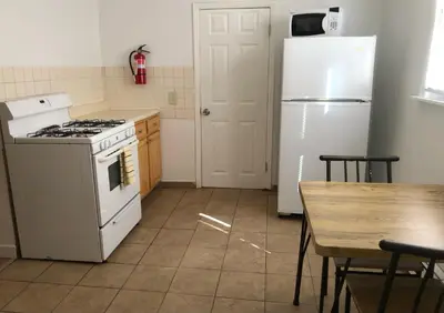 a kitchen with a stove and a refrigerator and a table at Private one-bedroom and one-bathroom apartment with private street entrance in convenient area, MetLife Stadium FIFA World Cup 35 minutes away in Perth Amboy