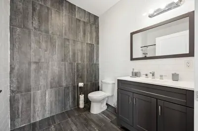 a bathroom with a toilet and a sink and a mirror at Lofts at Kearny - Rustic Chic 1-3BR Lofts with Quick NYC Access & On-Site Gym in Kearny