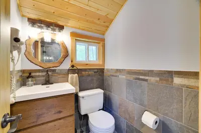 a bathroom with a toilet and a sink and a mirror at Secluded Cabin, Jacuzzi, Pool Table, King Bed & Fire Pit in Bushkill
