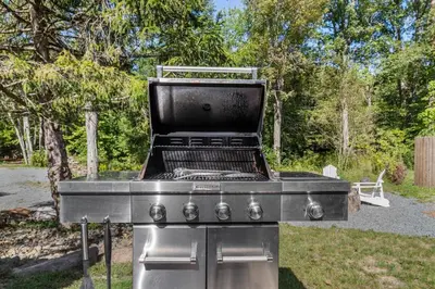 a stainless steel barbecue grill in a yard at Pocono River front Home near Camelback Resort in Barton Glen
