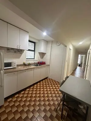 a kitchen with white cabinets and a table in it at AL Shami 408 in New York