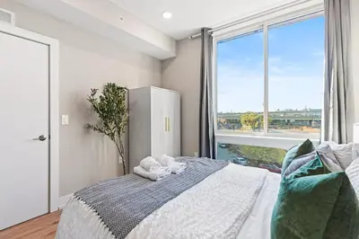 a bedroom with a bed and a large window at 10 mins to CenterCity, With Queen Bed, Views from RT! in Philadelphia