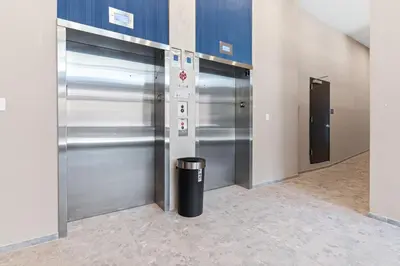 a hallway with two metal elevators and a trash can at 10 mins to CenterCity, With Queen Bed, Views from RT! in Philadelphia