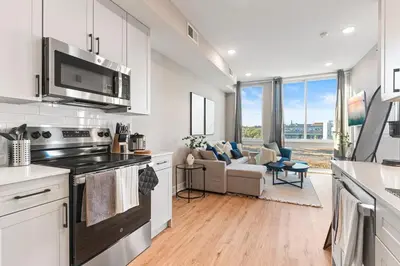 a kitchen with a stove top oven next to a living room at 10 mins to CenterCity, With Queen Bed, Views from RT! in Philadelphia