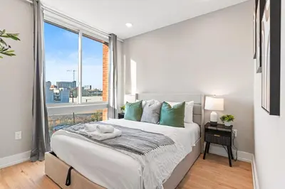 a bedroom with a bed and a large window at 10 mins to CenterCity, With Queen Bed, Views from RT! in Philadelphia