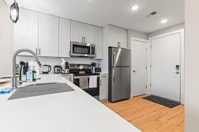 a kitchen with white cabinets and a stainless steel refrigerator at 10 mins to CenterCity, Sleeps 6, With Rooftop Views! in Philadelphia