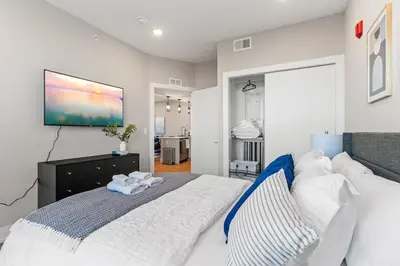 a bedroom with a large bed with a tv on the wall at 10 mins to CenterCity, Sleeps 6, With Rooftop Views! in Philadelphia