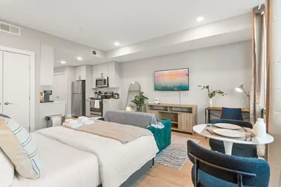a bedroom with two beds and a table and a kitchen at 5 mins to Fillmore! Queen Bed, Rooftop, NorthernLibs! in Philadelphia