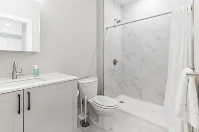 a white bathroom with a toilet and a shower at 5 mins to FishTown plus Old Town King Bed, Sleeps 4! in Philadelphia
