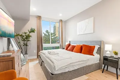 a bedroom with a bed with orange pillows and a window at 5 mins to Convention Center! Sleeps 4! With Rooftop! in Philadelphia