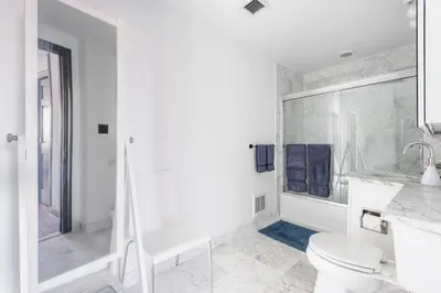 a white bathroom with a toilet and a shower at Stunning NYC Views! Free Gym! Doorman! Terrace! in New York