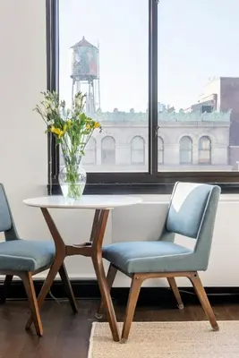 a table with two chairs and a vase with flowers at Stunning NYC Views! Free Gym! Doorman! Terrace! in New York