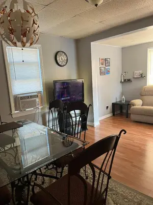 a living room with a table and chairs and a clock at Amazing House near EWR and NYC in Linden
