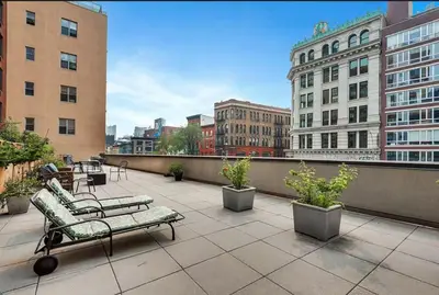 a patio with chairs and plants on a balcony at Doorman! High Floor! Views! Elevator! Free Gym! in New York