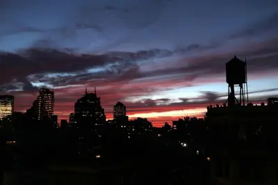 a city skyline at sunset with a water tower at Doorman! High Floor! Views! Elevator! Free Gym! in New York