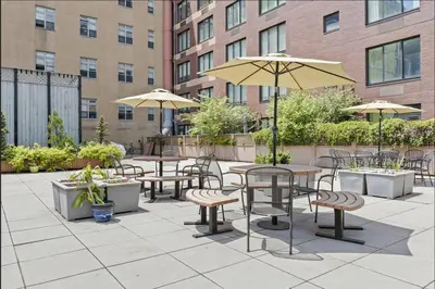 an outdoor patio with tables and chairs and umbrellas at Doorman! High Floor! Views! Elevator! Free Gym! in New York