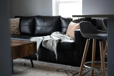 a black leather couch in a living room with a stool at Walk to WP Gate and Free Parking in Highland Falls