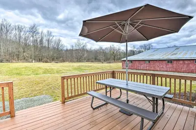 a picnic table with an umbrella on a wooden deck at Suite to Unwind Close to Ski Slopes in Pleasant Mount