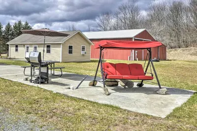 a red chair and a table with an umbrella at The Hideout Cottage Close to Ski Mountain in Pleasant Mount