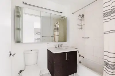 a bathroom with a sink and a toilet and a mirror at Blueground Midtown S gym AC nr Empire St NYC-1591 in New York