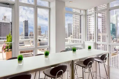 a large room with windows and white tables and chairs at Blueground Midtown S gym AC nr Empire St NYC-1591 in New York