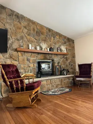 a living room with a stone wall with a fireplace at Cozy House