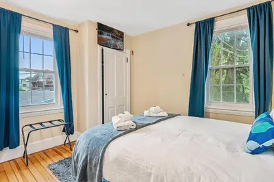 a bedroom with a large bed with blue curtains at NEW - Mainline Train, Colleges, Hospital in Bryn Mawr