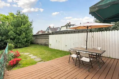 a table and chairs with an umbrella on a deck at NEW - Mainline Train, Colleges, Hospital in Bryn Mawr