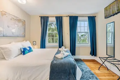 a bedroom with a large bed with blue curtains at NEW - Mainline Train, Colleges, Hospital in Bryn Mawr