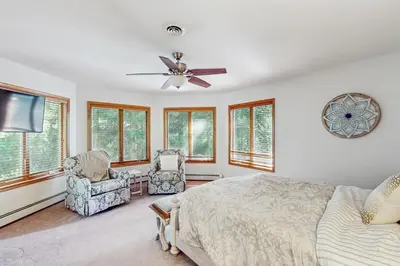 a bedroom with a bed and two chairs and a ceiling fan at Beach and Dock! Group-Friendly Albrightsville Gem in Towamensing Trails