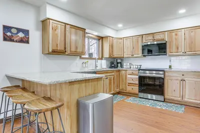 a kitchen with wooden cabinets and a counter with stools at Pocono Mountain Family Home with Deck and Grill in Saw Creek