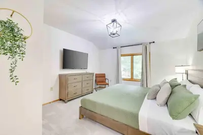 a white bedroom with a bed and a tv at Woodlands Hideaway- Hot Tub Grill & Games in Albrightsville