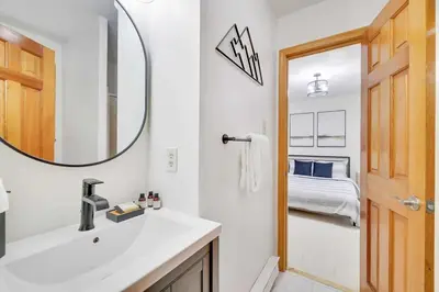a bathroom with a sink and a mirror and a bed at Woodlands Hideaway- Hot Tub Grill & Games in Albrightsville