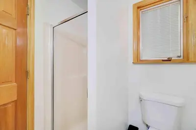 a bathroom with a shower and a toilet and a window at Woodlands Hideaway- Hot Tub Grill & Games in Albrightsville