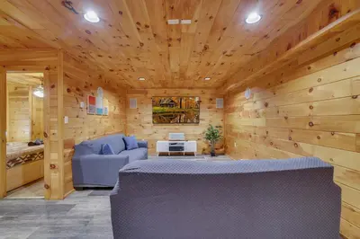 a room with a blue couch and wooden walls at Cozy Freeland Retreat- Firepit Pool Table Hot Tub in White Haven