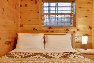 a bedroom with a bed with wooden walls and a window at Cozy Freeland Retreat- Firepit Pool Table Hot Tub in White Haven